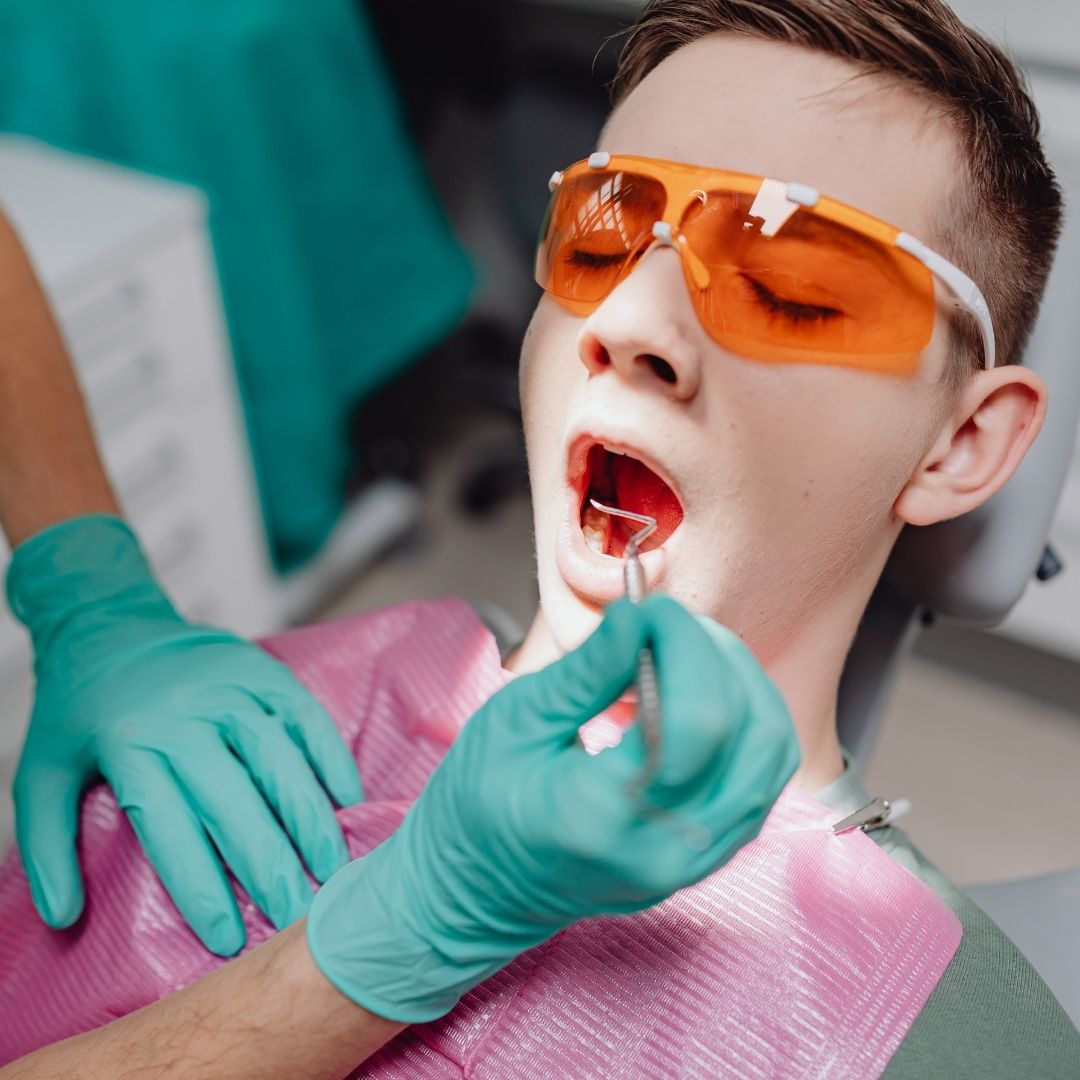 A teenage patient sits in dental chair